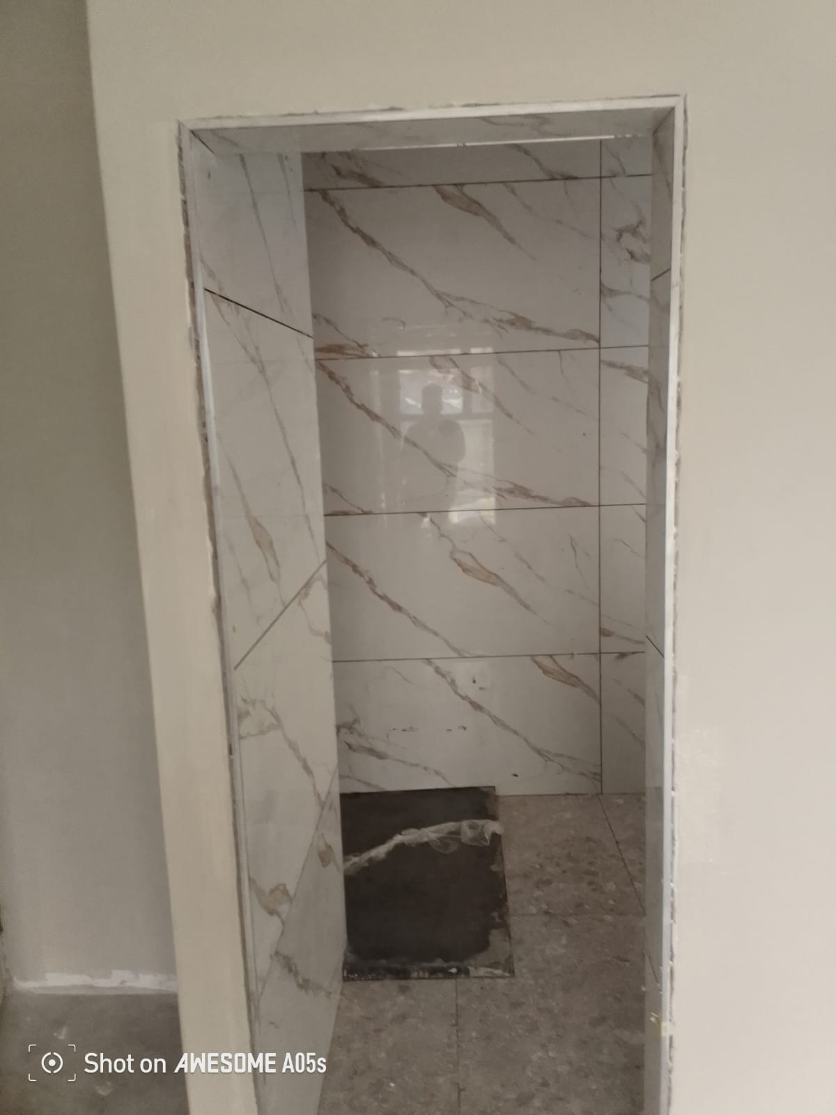 Marble-look porcelain bathroom doorway view, freshly tiled